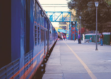 people standing beside blue train thumbnail