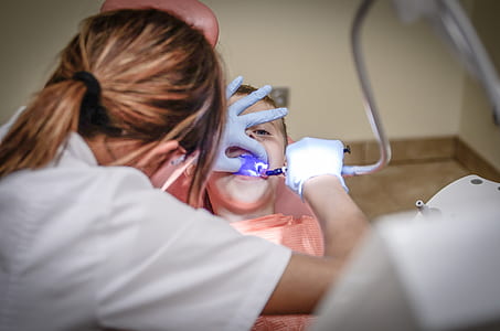 woman wearing scrub shirt checking up girl's teeth thumbnail