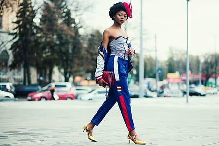 Woman Wearing White Sweetheart Neckline Shirt With Blue and Red Pants Walking Across the Street thumbnail