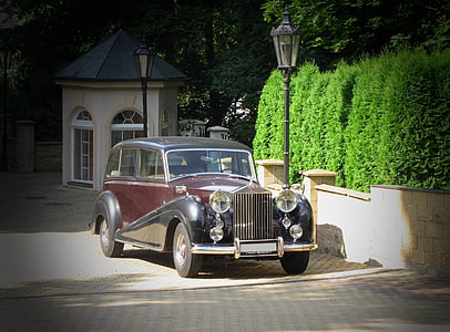classic black and brown hardtop car parked beside wall during daytime thumbnail