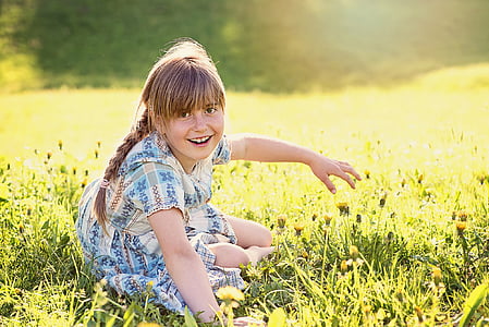 girl wearing blue dress sitting on green grass field thumbnail