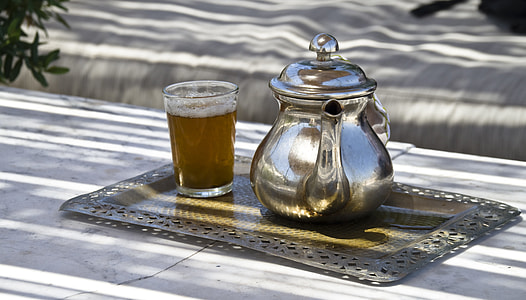 silver teapot beside glass cup filled on silver tray thumbnail