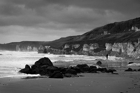 grayscale photo of sea shore with rocks thumbnail
