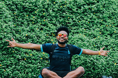 man raising his hands sitting infront of plant at daytime thumbnail