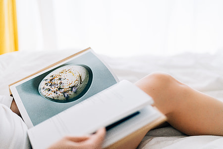 person reading book on white bed thumbnail