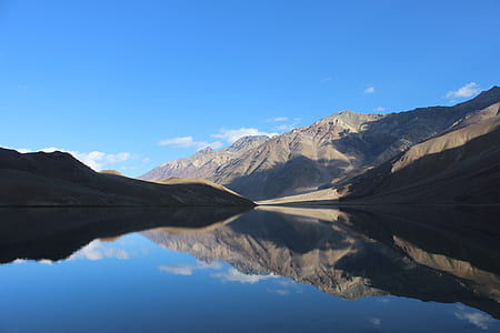 body of water surrounded with mountains under blue skies thumbnail