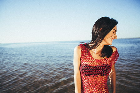 smiling woman wearing red mesh sleeveless top beside beach during daytime thumbnail