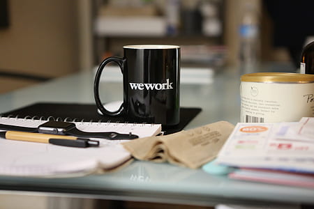 black wework-printed ceramic mug on black mousepad near white notebook thumbnail