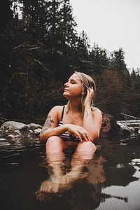 woman sitting on body of water near trees thumbnail