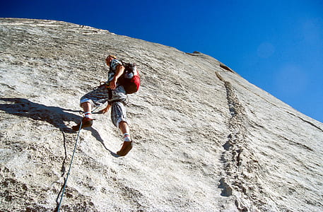 man climbing on rock under blue sky thumbnail