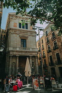 Brown Concrete Building With People Sitting on Patio Sets Photo Taken thumbnail