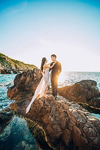 Man and Woman Standing on Brown Rock Under Blue Sky thumbnail