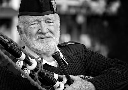 grayscale photography of man holding bagpipe thumbnail