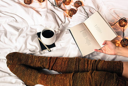 person holding book near white ceramic mug thumbnail