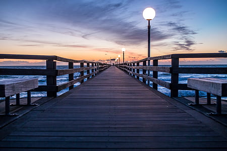 lighted dock above body of water under gray clouds at golden hour thumbnail