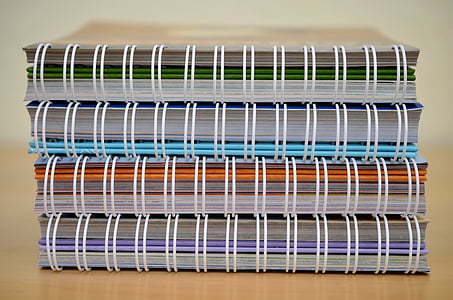 four assorted-color spiral notebooks on beige surface thumbnail