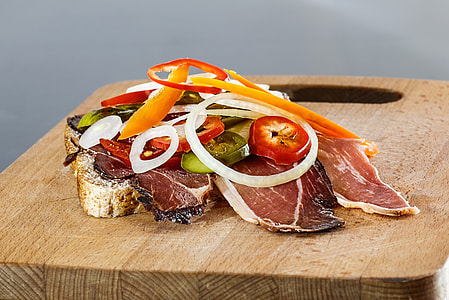 fish meat on brown chopping board with sliced tomato and onion toppings thumbnail