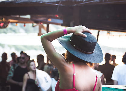 selective focus photography of woman holding her hat while standing in front of crows thumbnail