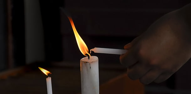 person holding white candle thumbnail