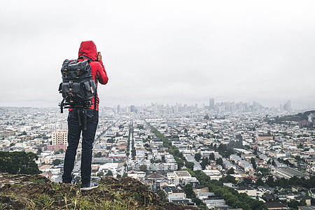 man standing on clip overlooking the city while taking photography thumbnail