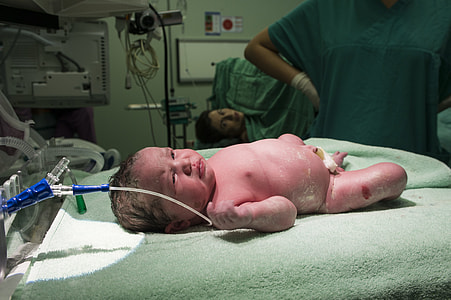 baby lying on green textile near hospital machine thumbnail