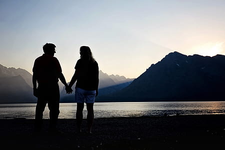 silhouette of man and woman holding hands near body water thumbnail