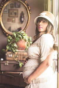 pregnant woman standing inside room near window during daytime thumbnail