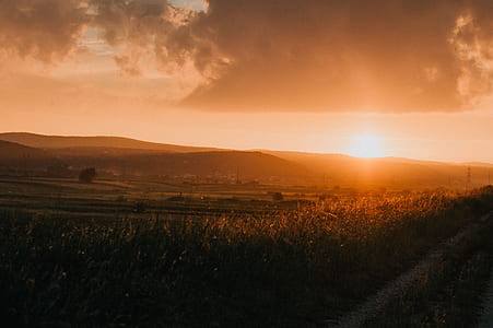 grass field under cloudy sky during sunset thumbnail
