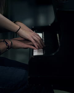 two pairs of hands playing the piano keys in closeup photo thumbnail