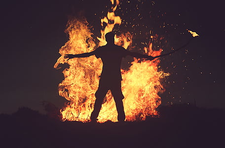 silhouette of man standing in front of bone fire during nighttime thumbnail