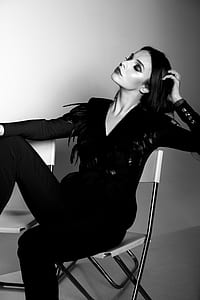 grayscale photo of woman sitting on folding chair thumbnail