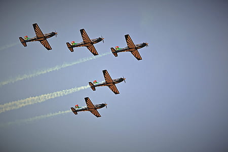 low angle of five black-and-brown planes making smoke trail thumbnail