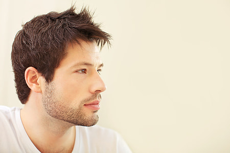 man in white shirt sitting in front of white concrete wall thumbnail