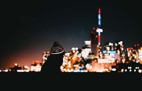 selective focus photography of person wearing knit cap in front of buildings during nighttime thumbnail