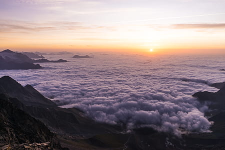 mountain peaks surrounded by clouds at golden hour thumbnail