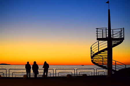 silhouette photography of three person near spiral tower thumbnail