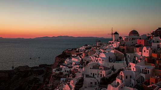 white concrete buildings on hill near body of water at golden hour thumbnail