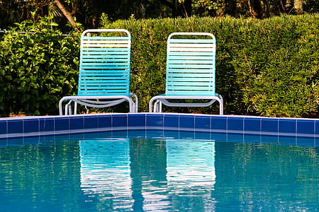 two white steel lounge chairs in front of in ground pool thumbnail