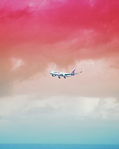 white Qatar Airlines airplane below red and gray clouds thumbnail