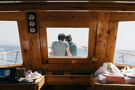 woman and man sitting near edge of boat facing ocean thumbnail