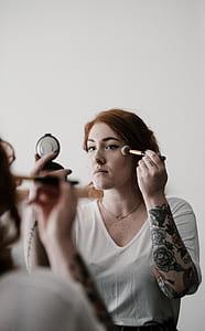 woman holding makeup brush and portable mirror thumbnail