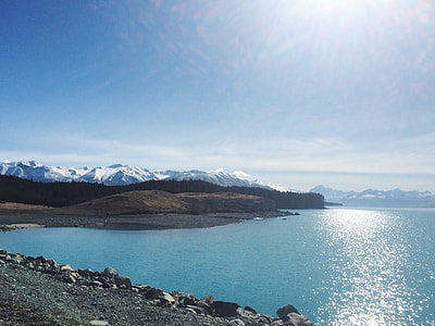 mountain beside body of water under blue sky thumbnail