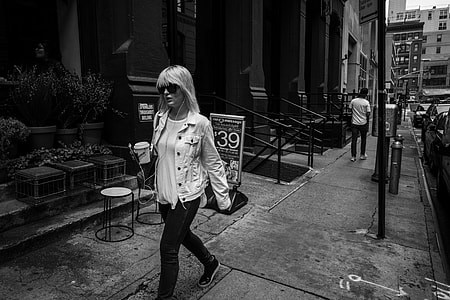 grayscale photo of woman walking on street thumbnail