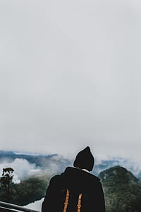 person facing mountain landscape with clouds thumbnail