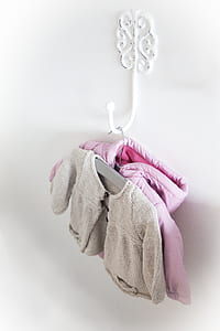 pink zip-up jacket and gray sweatshirt hanging on wall thumbnail