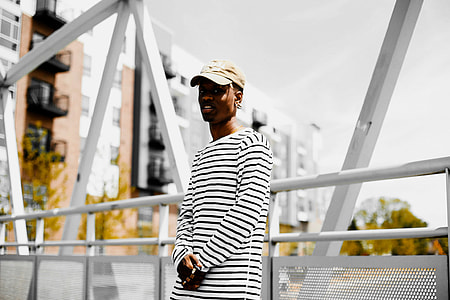man leaning backwards on white metal bridge fence thumbnail