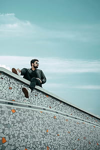 sitting man on concrete pavement under clear sky thumbnail