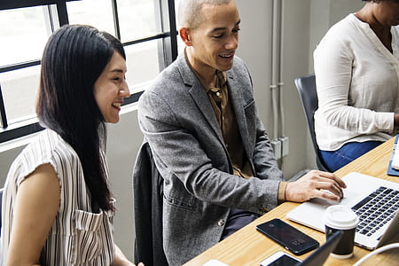 man in gray blazer using laptop beside woman in striped shirt thumbnail
