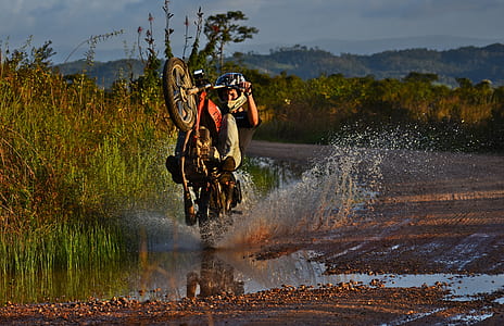man riding red and white motor cycle thumbnail