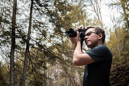 person carrying black DSLR camera and taking photo thumbnail